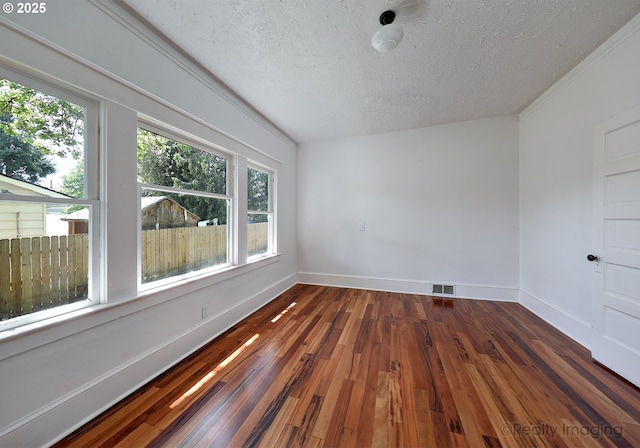 spare room with a textured ceiling, baseboards, and dark wood finished floors