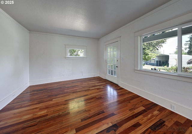 spare room with dark wood-type flooring, ornamental molding, and baseboards