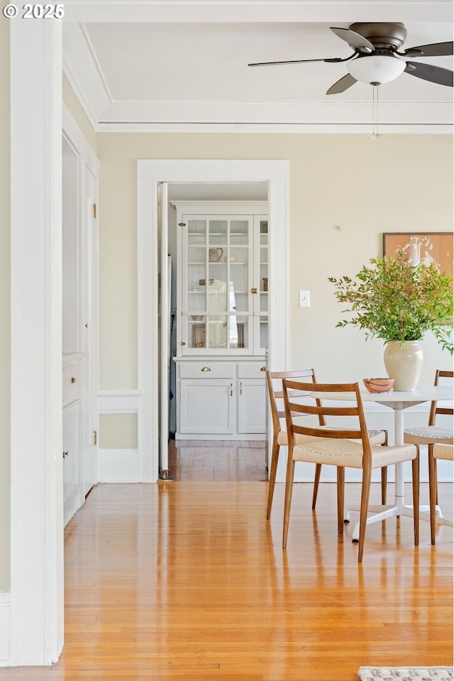 dining space with ceiling fan, ornamental molding, and light hardwood / wood-style floors