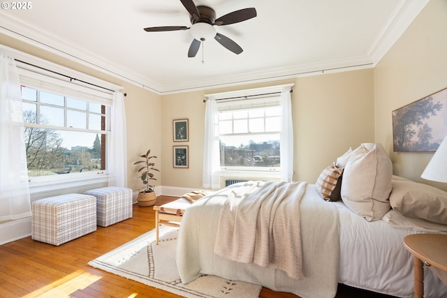 bedroom with multiple windows, crown molding, ceiling fan, and hardwood / wood-style flooring