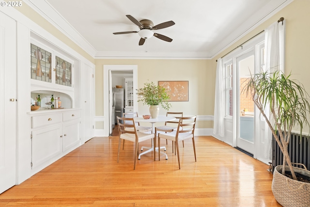 dining space featuring crown molding, ceiling fan, radiator, and light wood-type flooring