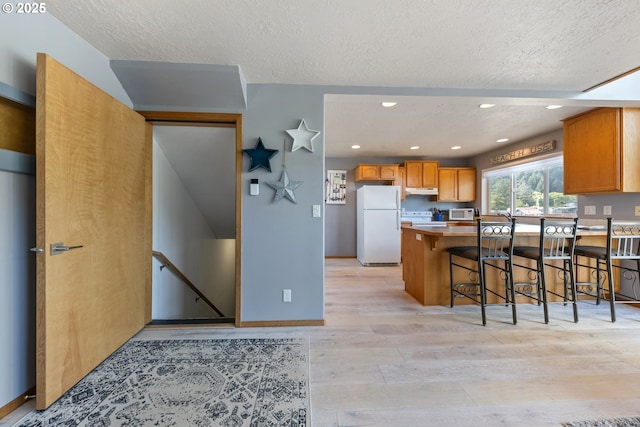 33645 Resort Dr, Pacific City, OR 97135 - kitchen with white appliances, light wood-type flooring, a textured ceiling, light countertops, and a peninsula
