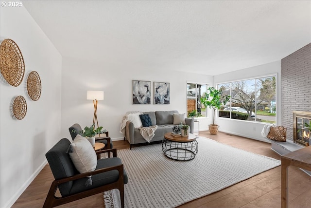 living area with a brick fireplace, wood finished floors, and baseboards