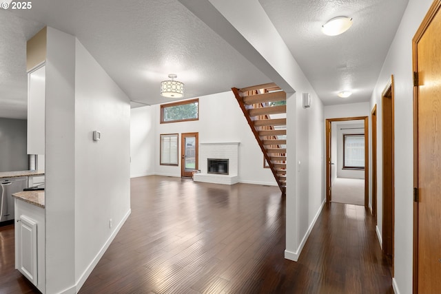 hall featuring stairway, dark wood-style floors, baseboards, and a textured ceiling