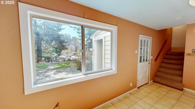 foyer entrance featuring light tile patterned floors, stairway, and baseboards