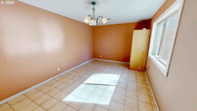 spare room with baseboards and a chandelier