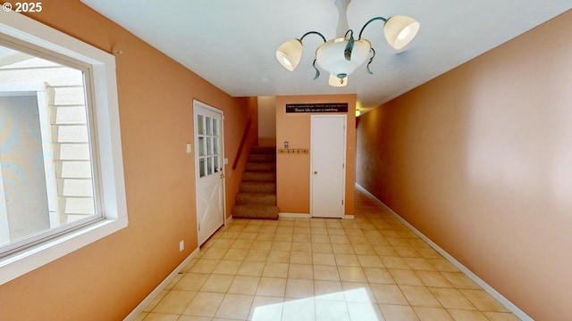 hallway featuring light tile patterned floors, stairway, and baseboards