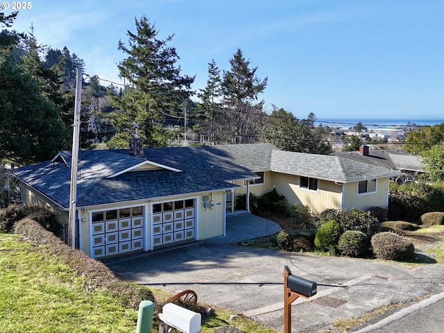 single story home featuring aphalt driveway, an attached garage, a water view, and roof with shingles