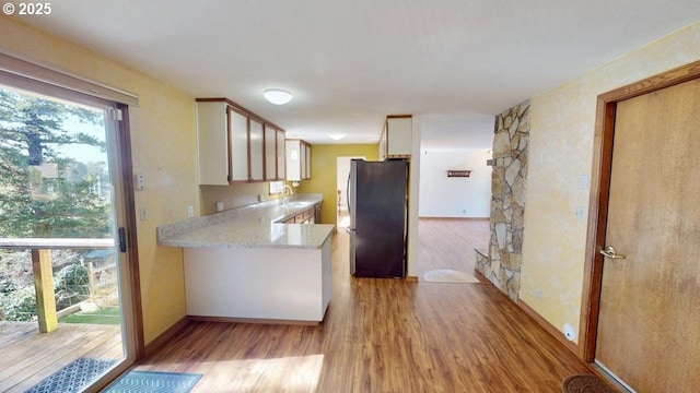 kitchen with baseboards, white cabinetry, light wood-style flooring, and freestanding refrigerator