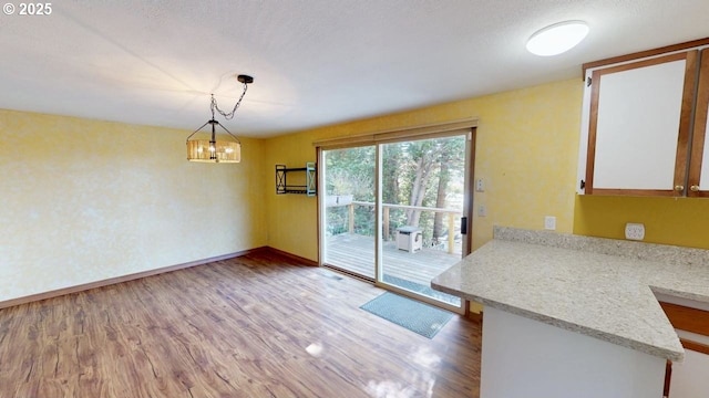 unfurnished dining area with a chandelier, light wood-type flooring, and baseboards