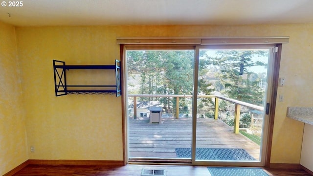 entryway with a wealth of natural light, visible vents, baseboards, and wood finished floors