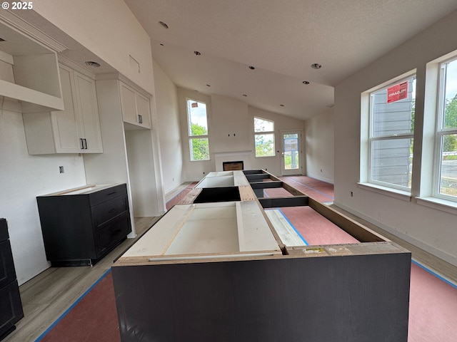 407 SE Shetterly Dr, Dallas, OR 97338 - kitchen with vaulted ceiling, light wood finished floors, a fireplace, white cabinetry, and light countertops