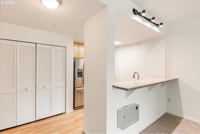 10800 SE 17th Cir Unit Q178, Vancouver, WA 98664 - kitchen featuring stainless steel fridge with ice dispenser, a kitchen breakfast bar, baseboards, a peninsula, and light stone counters