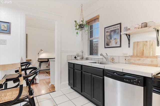 kitchen featuring sink, stainless steel dishwasher, and light tile patterned flooring