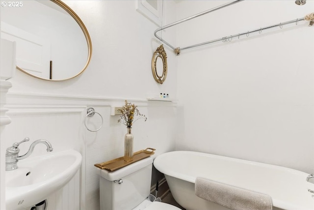 bathroom featuring a washtub, sink, and toilet