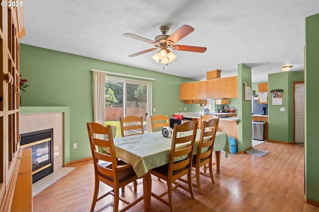 112 NE 11th St, Hermiston, OR 97838 - dining room featuring light wood-style flooring, ceiling fan, and a tiled fireplace