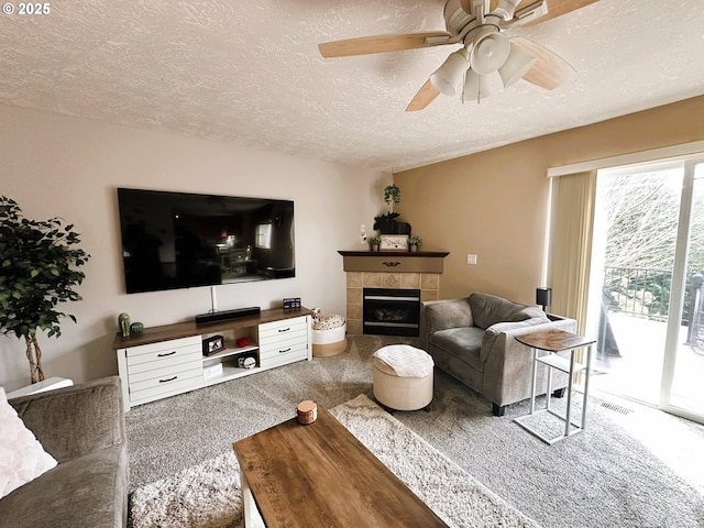 carpeted living room with visible vents, a fireplace, a textured ceiling, and a ceiling fan