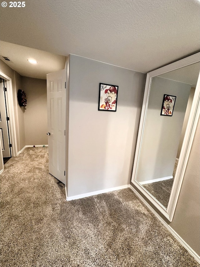 corridor featuring carpet flooring, visible vents, a textured ceiling, and baseboards