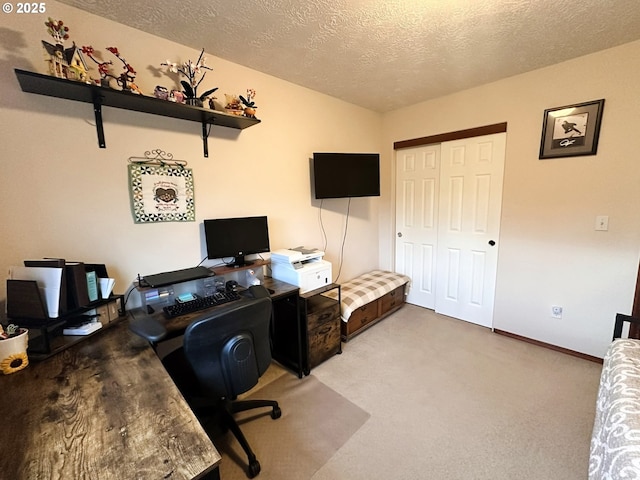 office space featuring light colored carpet, a textured ceiling, and baseboards