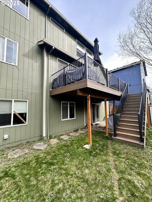 back of property with stairway, a wooden deck, and a yard