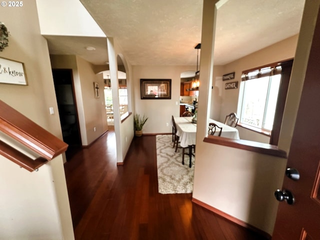 entryway with arched walkways, baseboards, and wood finished floors