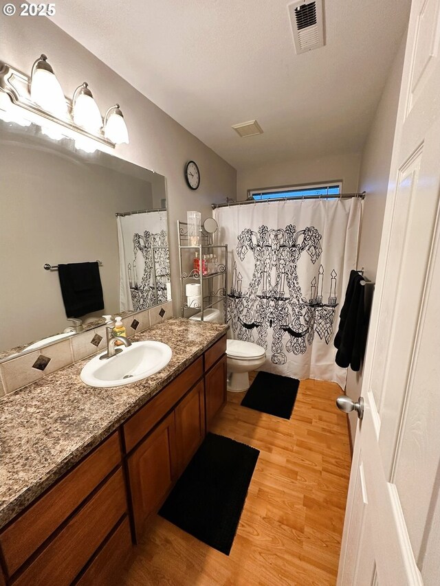 bathroom featuring vanity, wood finished floors, visible vents, curtained shower, and toilet