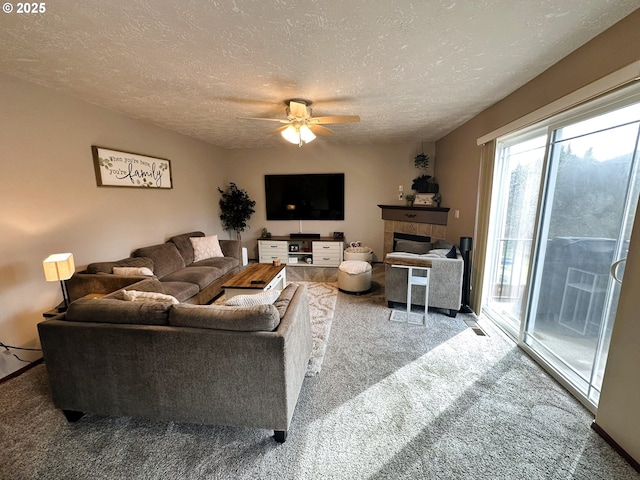 carpeted living area featuring a textured ceiling, ceiling fan, and a tiled fireplace