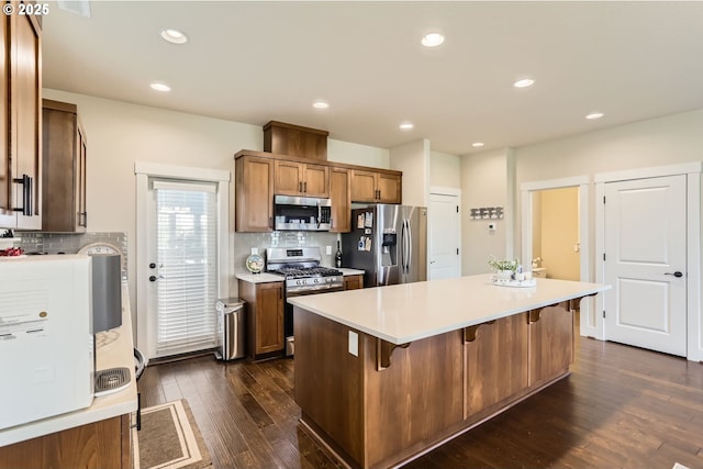 12967 SW River Terrace Blvd, Beaverton, OR 97007 - kitchen featuring appliances with stainless steel finishes, decorative backsplash, dark wood-style flooring, a breakfast bar, and recessed lighting