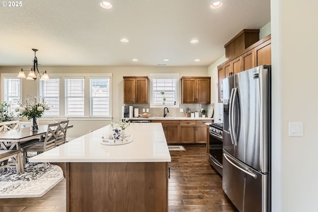 12967 SW River Terrace Blvd, Beaverton, OR 97007 - kitchen with stainless steel appliances, a sink, brown cabinets, light countertops, and a center island