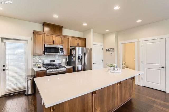 12967 SW River Terrace Blvd, Beaverton, OR 97007 - kitchen featuring appliances with stainless steel finishes, dark wood finished floors, tasteful backsplash, light countertops, and brown cabinets