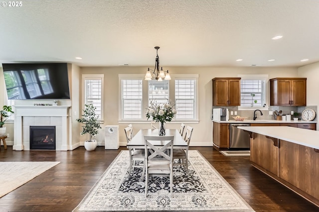 12967 SW River Terrace Blvd, Beaverton, OR 97007 - dining room featuring dark wood-style floors, recessed lighting, a chandelier, a tiled fireplace, and baseboards