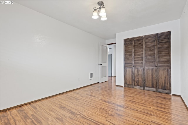 unfurnished bedroom with light hardwood / wood-style floors, a chandelier, and a closet