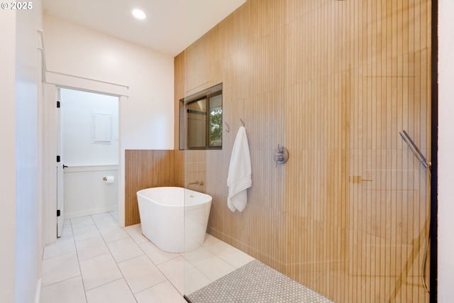 bathroom with a tub to relax in, tile walls, and tile patterned flooring