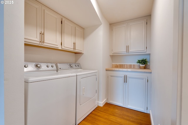 laundry room with light hardwood / wood-style flooring, independent washer and dryer, and cabinets