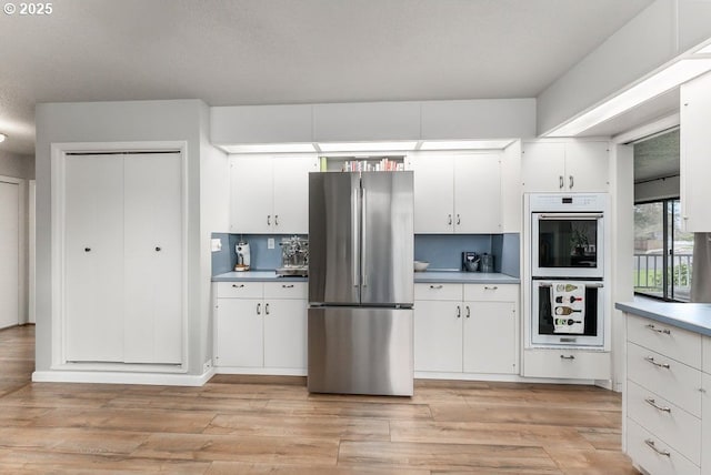 185 W Oriole Dr, Roseburg, OR 97471 - kitchen with light wood finished floors, white cabinets, freestanding refrigerator, and white double oven