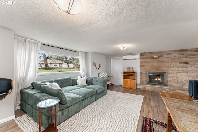 185 W Oriole Dr, Roseburg, OR 97471 - living room with a wall mounted AC, a large fireplace, baseboards, a textured ceiling, and wood finished floors