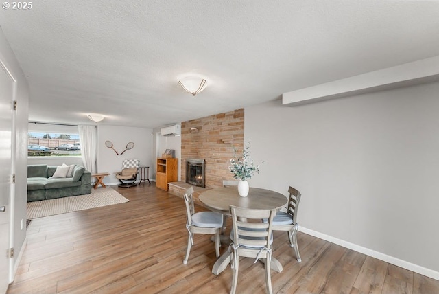 185 W Oriole Dr, Roseburg, OR 97471 - dining area with baseboards, light wood-type flooring, a wall mounted AC, and a fireplace