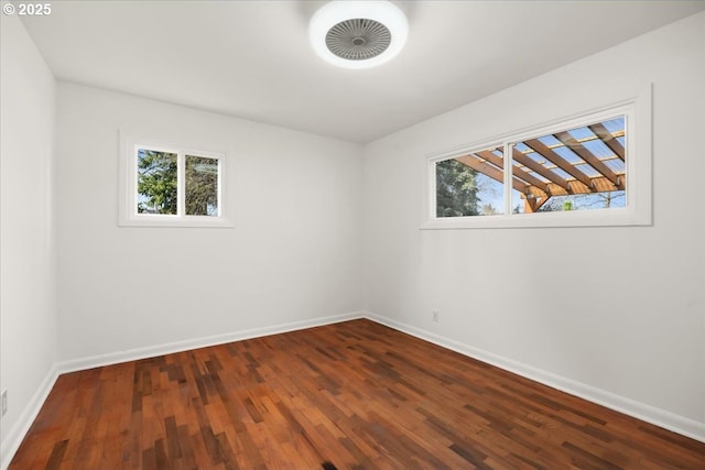 unfurnished room with dark wood-style flooring, plenty of natural light, and baseboards