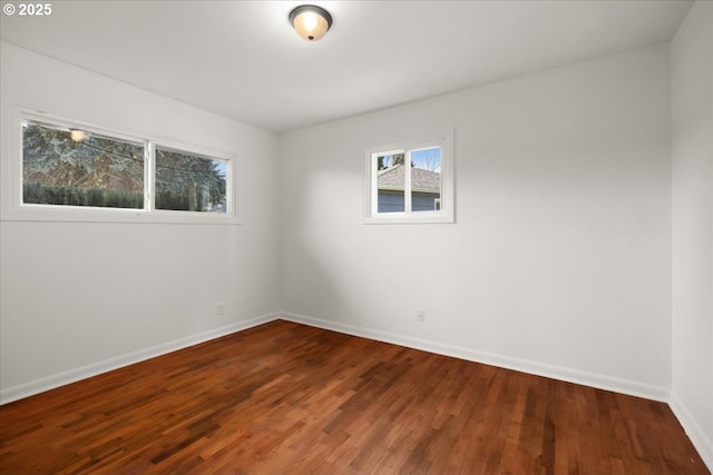 spare room featuring baseboards and wood finished floors