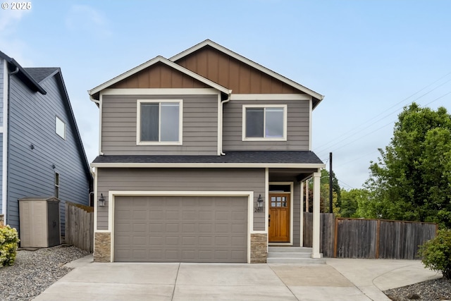 craftsman inspired home with board and batten siding, fence, stone siding, and a garage