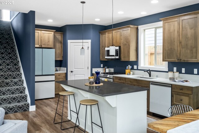 kitchen featuring white appliances, a breakfast bar area, a center island, a sink, and dark wood finished floors