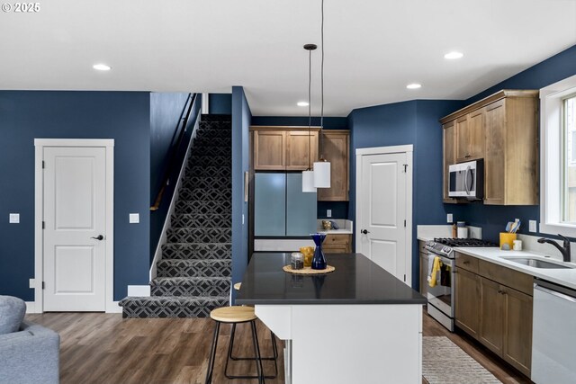 kitchen with a sink, dark wood finished floors, stainless steel appliances, recessed lighting, and a kitchen bar