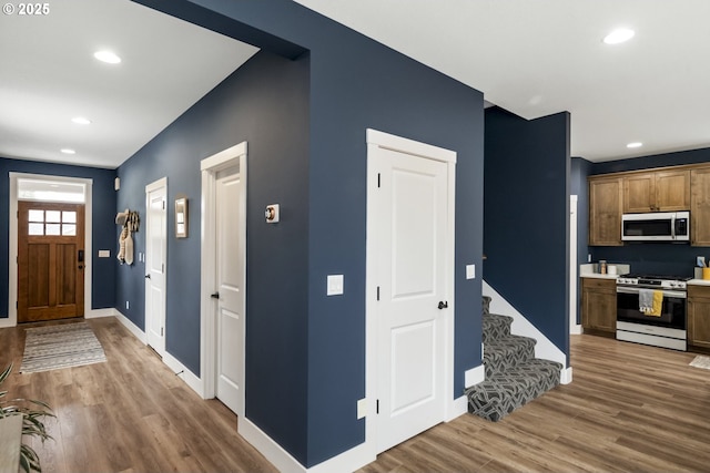 entryway with recessed lighting, baseboards, wood finished floors, and stairway