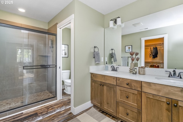 full bathroom featuring a sink, a stall shower, toilet, and wood finished floors