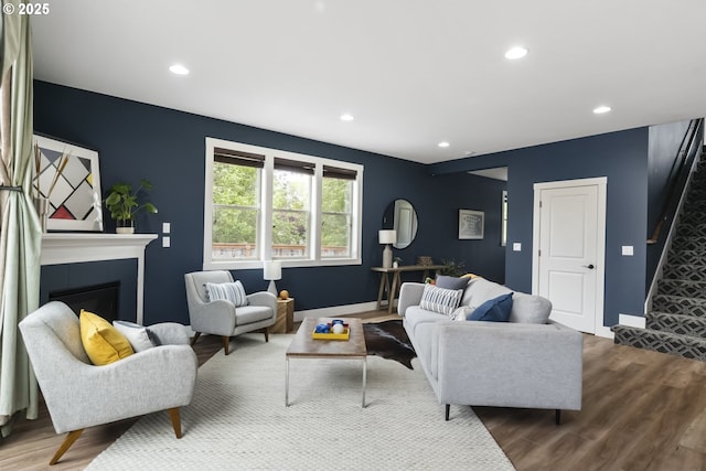 living area with wood finished floors, stairway, baseboards, a glass covered fireplace, and recessed lighting