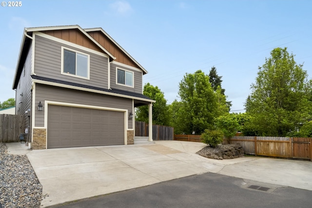 exterior space featuring concrete driveway, fence, board and batten siding, and an attached garage