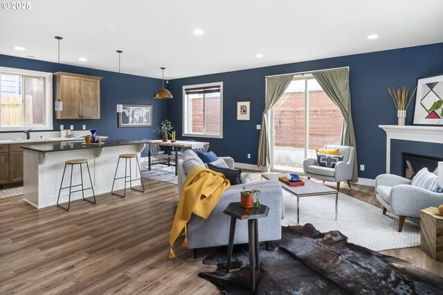 living room with recessed lighting, baseboards, a glass covered fireplace, and dark wood-style floors