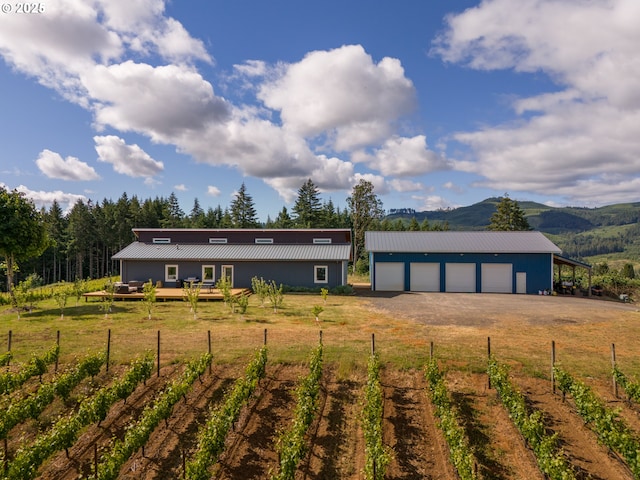 view of front facade featuring a detached garage, fence, an outdoor structure, and a vegetable garden