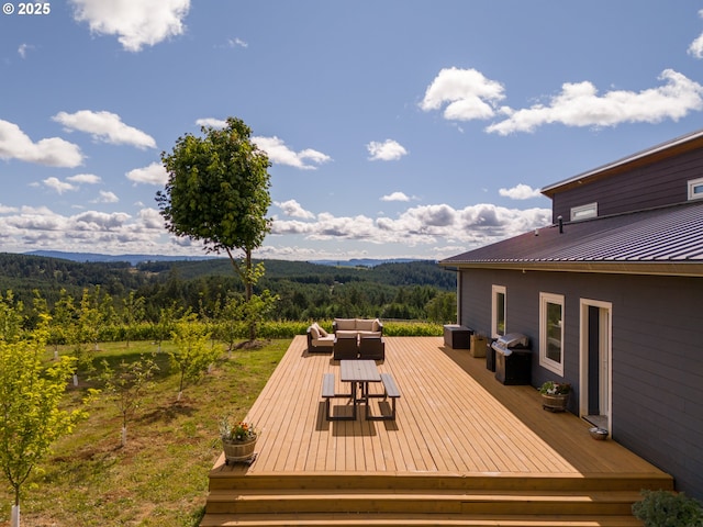 wooden deck featuring an outdoor living space, grilling area, and a forest view