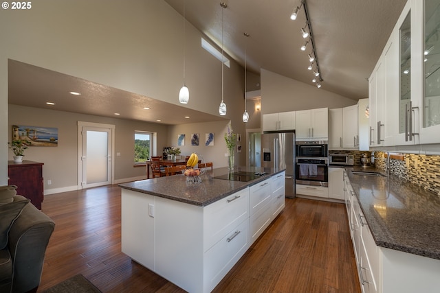 kitchen featuring stainless steel refrigerator with ice dispenser, black electric cooktop, open floor plan, glass insert cabinets, and dark wood-type flooring